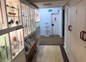 Access to toilets. Displays of ceramic objects in glass cases along the wall to the left.