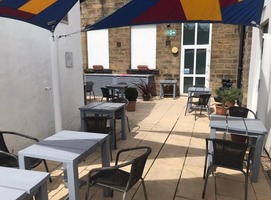 Cooper Gallery seating area near the side entrance. Cafe tables and chairs under an awning on a patio.